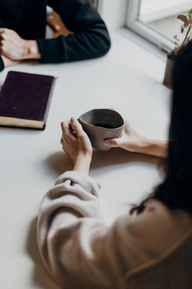 Zwei Frauen am Tisch mit einer Tasse Kaffee und einem Notizbuch als Verbildlichung für meine SEO-Angebote
